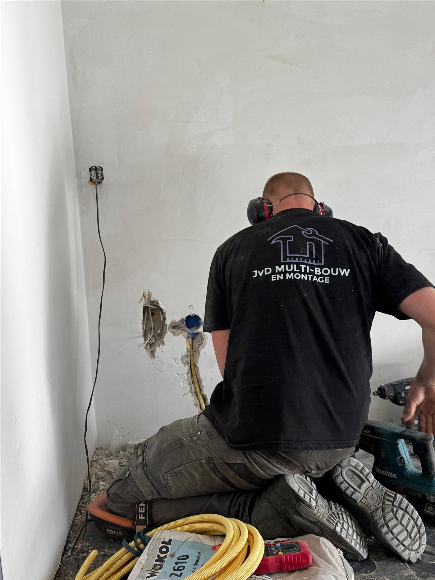 JvD aan het werk tijdens een renovatie, met het bedrijfslogo op de werkkleding